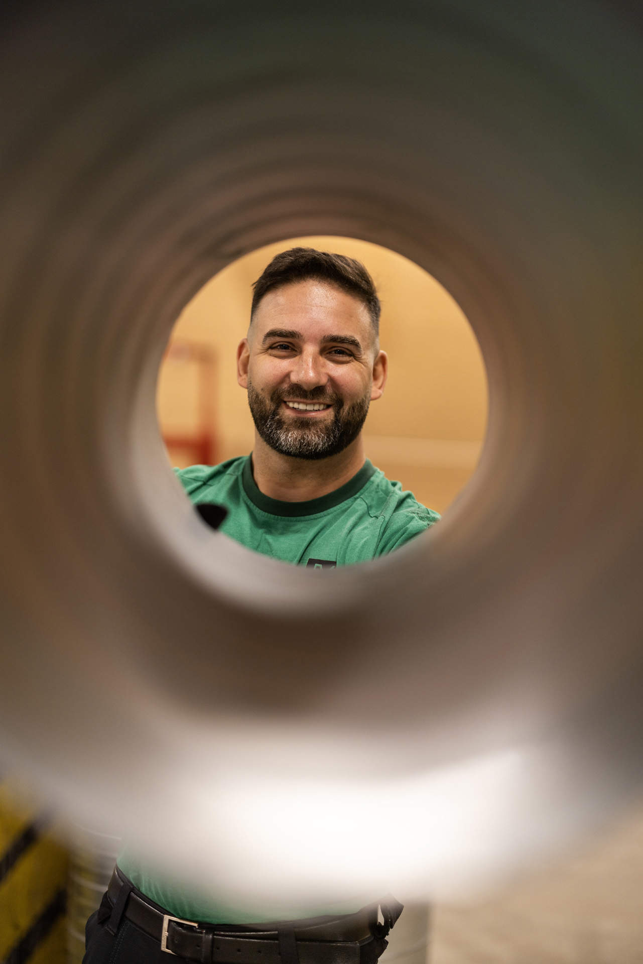 En smilende medarbejder hos JV Ventilation kigger gennem et indeklima ventilationsrør